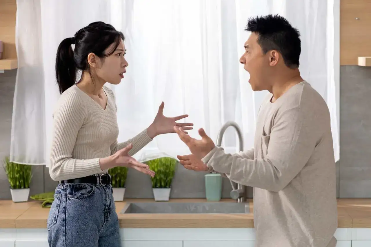 Pareja discutiendo en la cocina, un momento de **reflexiones de pareja en crisis** que podr&iacute;a llevar a una reconciliaci&oacute;n o a un final.