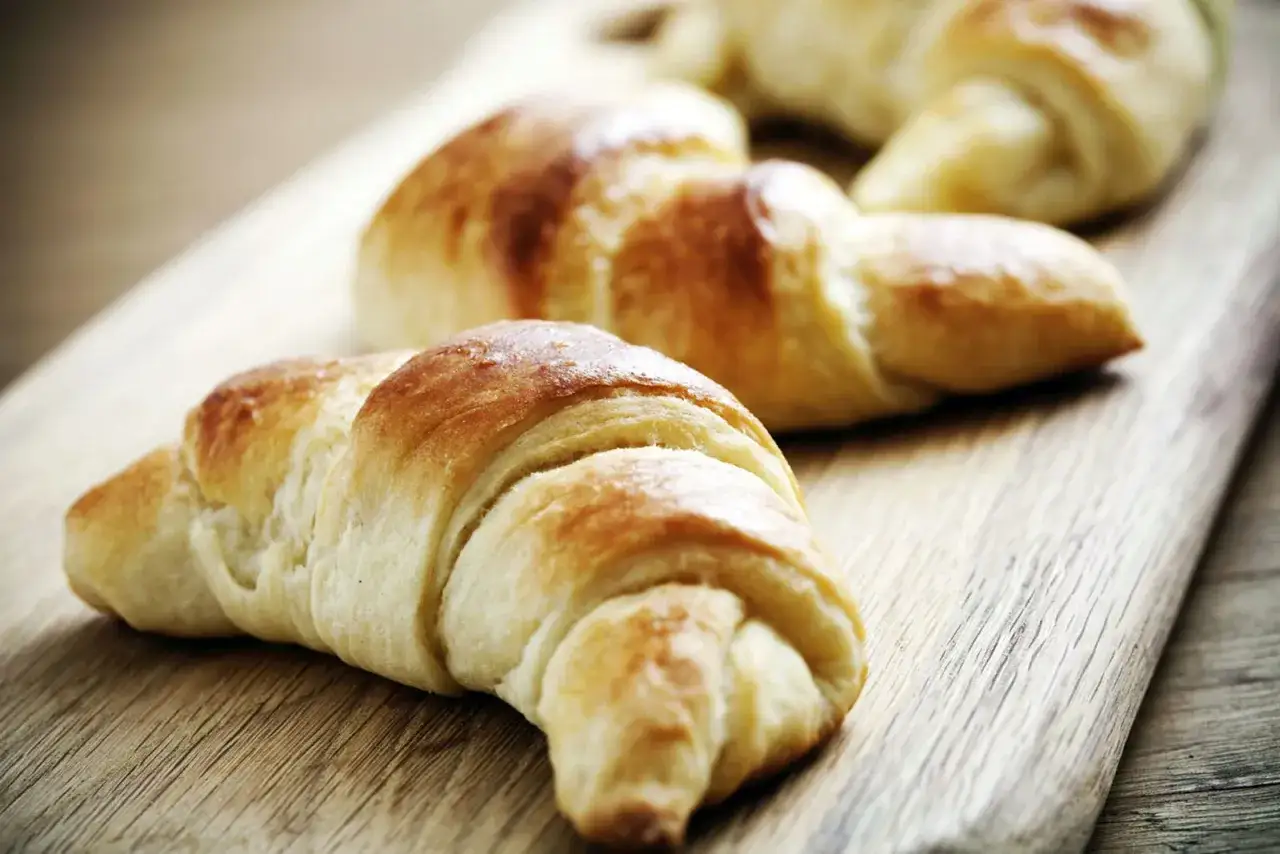 Croissants dorados y esponjosos, listos para disfrutar. El resultado perfecto de hacer croissant con hojaldre.
