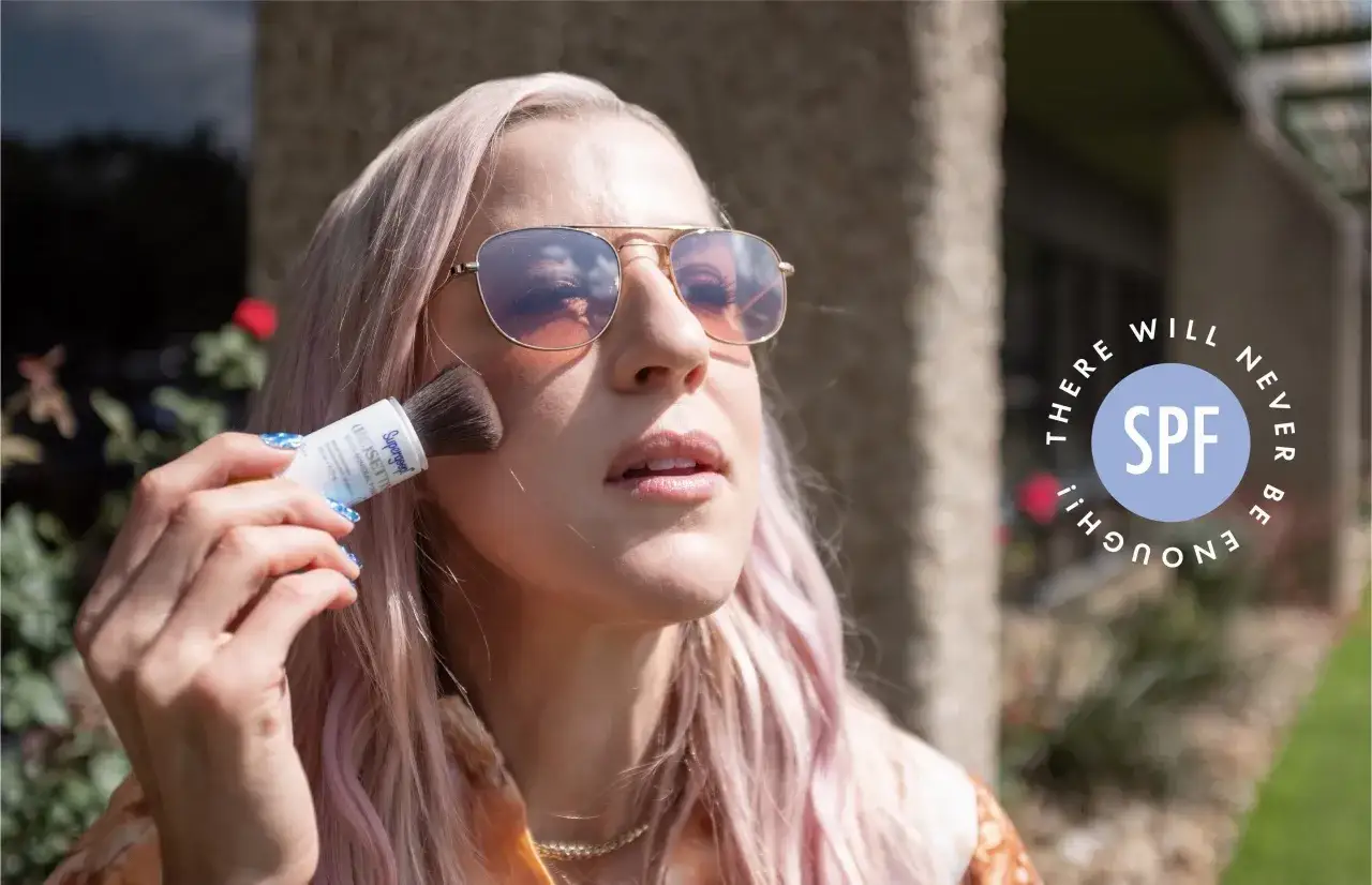 Kobieta w okularach przeciwsłonecznych aplikuje puder z filtrem SPF na twarz. Reaplikacja SPF to klucz do ochrony.