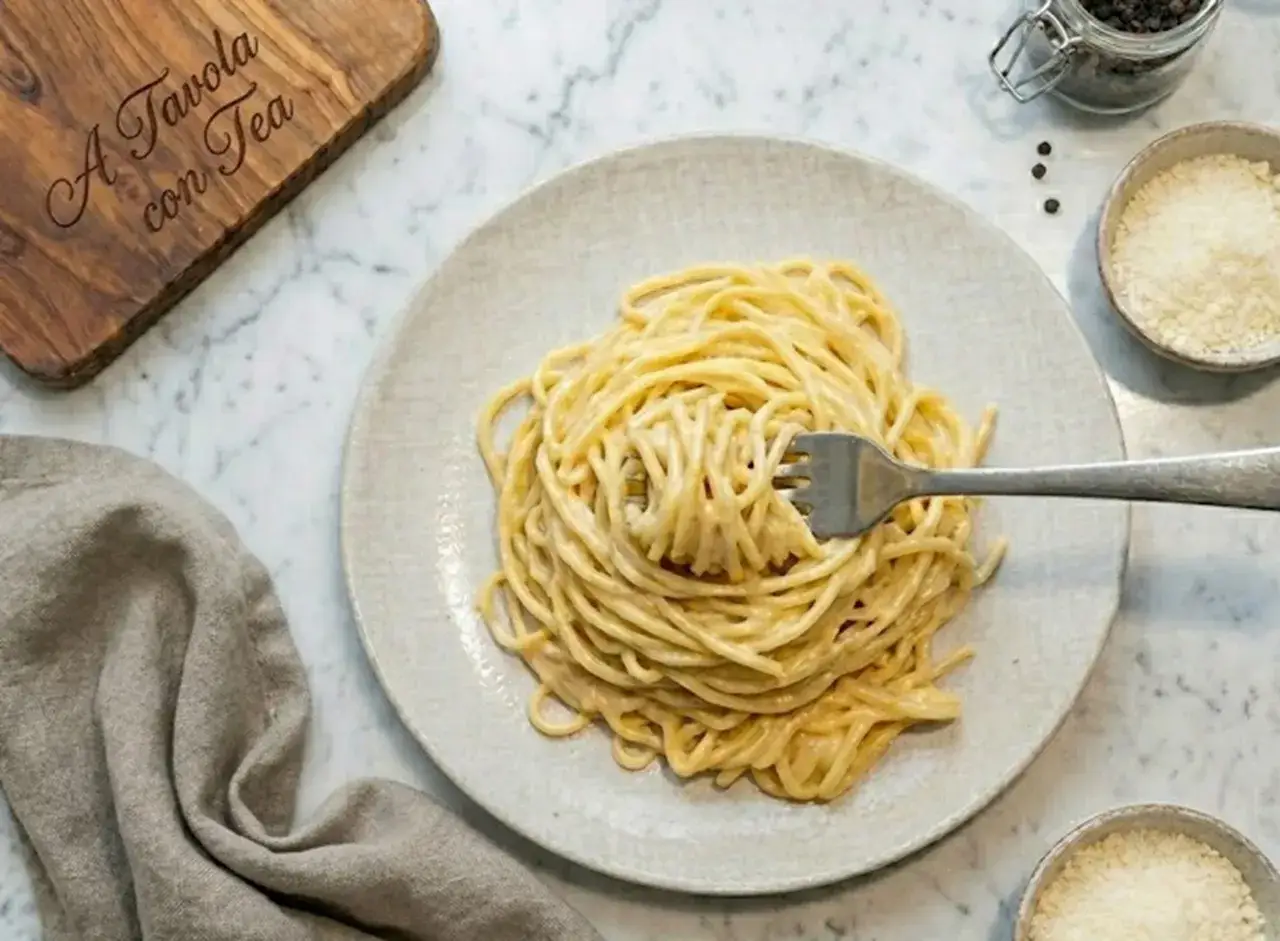Un piatto di spaghetti cremosi, conditi con una salsa alla panna e parmigiano, pronti per essere gustati.
