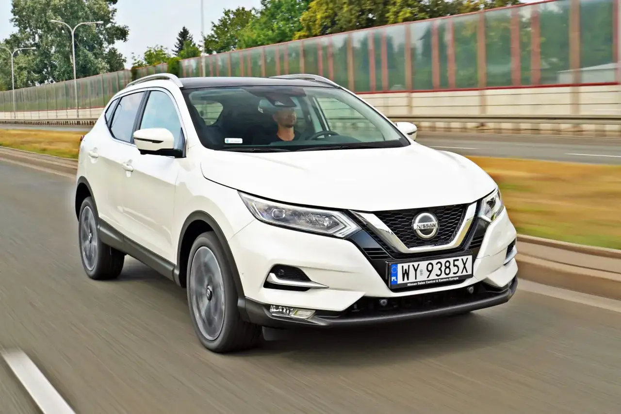 Biały Nissan Qashqai jedzie po drodze. Sprawdź aktualną nissan qashqai cena i oferty.