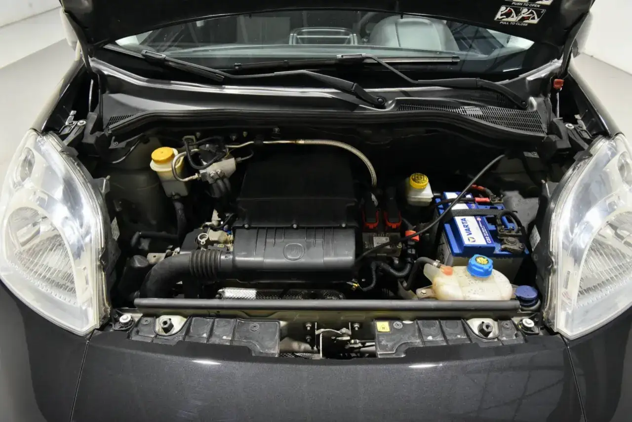 Vano motore Fiat Qubo con batteria Varta, impianto di raffreddamento e coperchio motore.