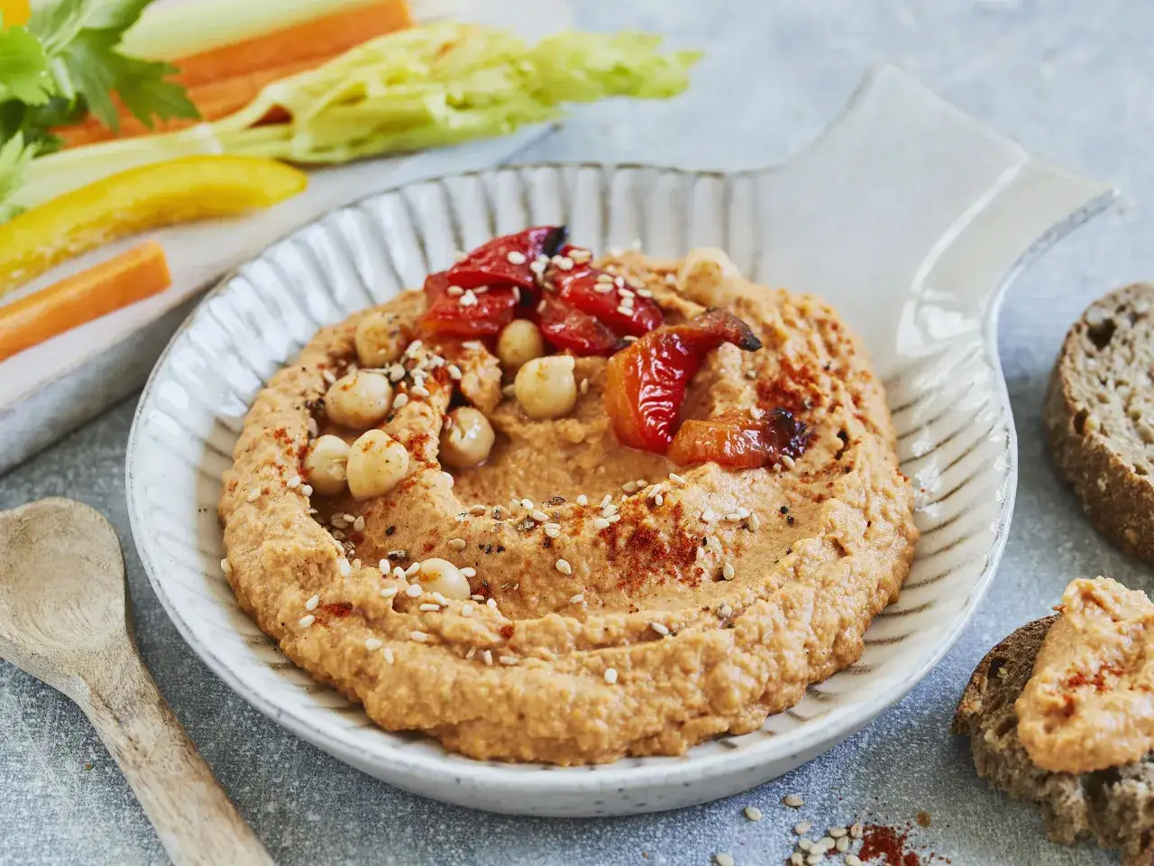 Cremiger Hummus mit ger&ouml;steten Paprika und Kichererbsen, garniert mit Sesam und Paprikapulver. Das beste Hummus Rezept f&uuml;r einen gesunden Snack mit Gem&uuml;sesticks und Brot.
