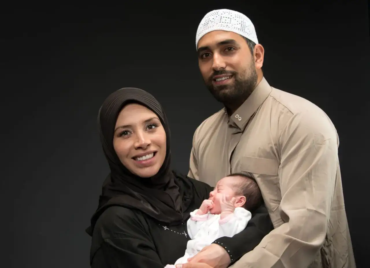 Un couple musulman souriant tient leur nouveau-né. Les jours de naissance et leur sacrifice en Islam sont symbolisés par cette famille.