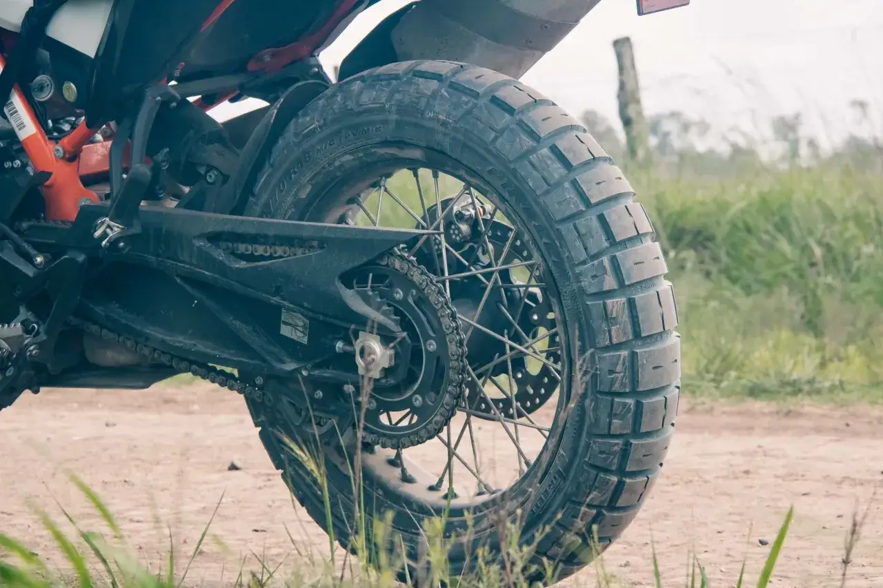 Tylne koło motocykla z oponą Pirelli Scorpion Rally STR na szutrowej drodze, gotowe na przygodę.