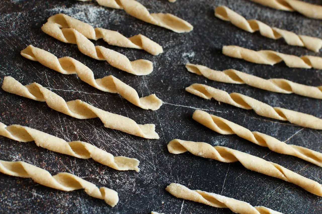 Sagne torte fatte in casa, pasta fresca attorcigliata su una superficie scura, pronte per essere cucinate.