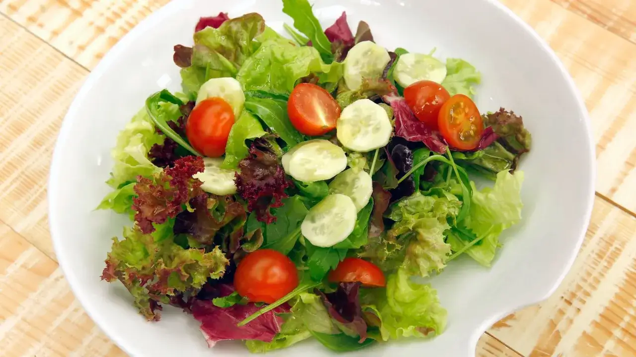 Fresca ensalada de lechuga con tomates cherry y rodajas de pepino, un plato ligero y saludable.