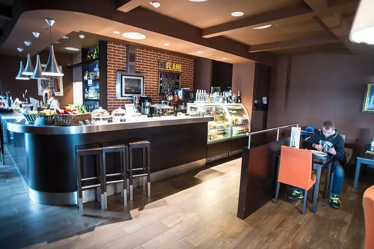 Wnętrze jednej z restauracji na lotnisku w Gdańsku. Przy ladzie siedzi mężczyzna, delektując się posiłkiem.
