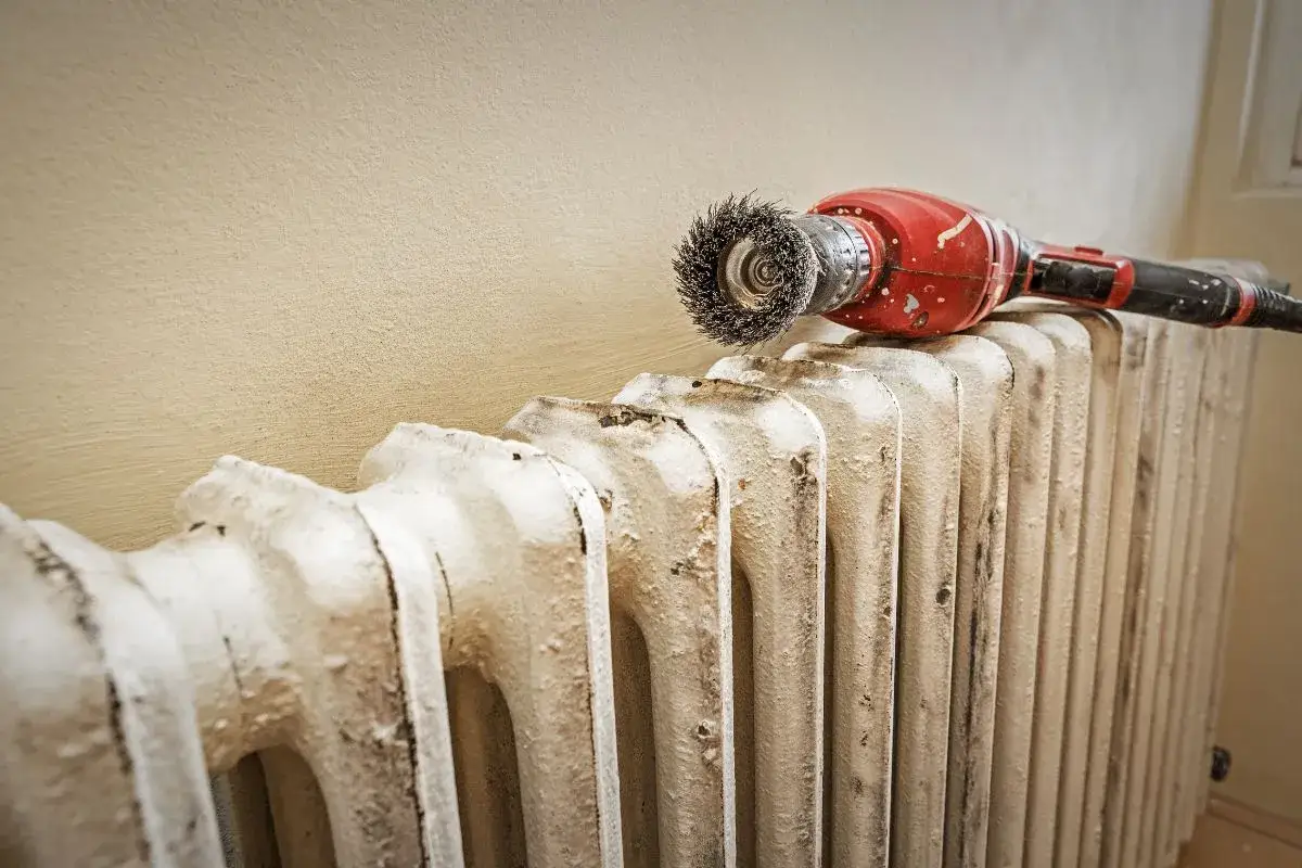 Attrezzo per pulire un vecchio termosifone in ghisa, pronto per essere preparato per imbiancare.