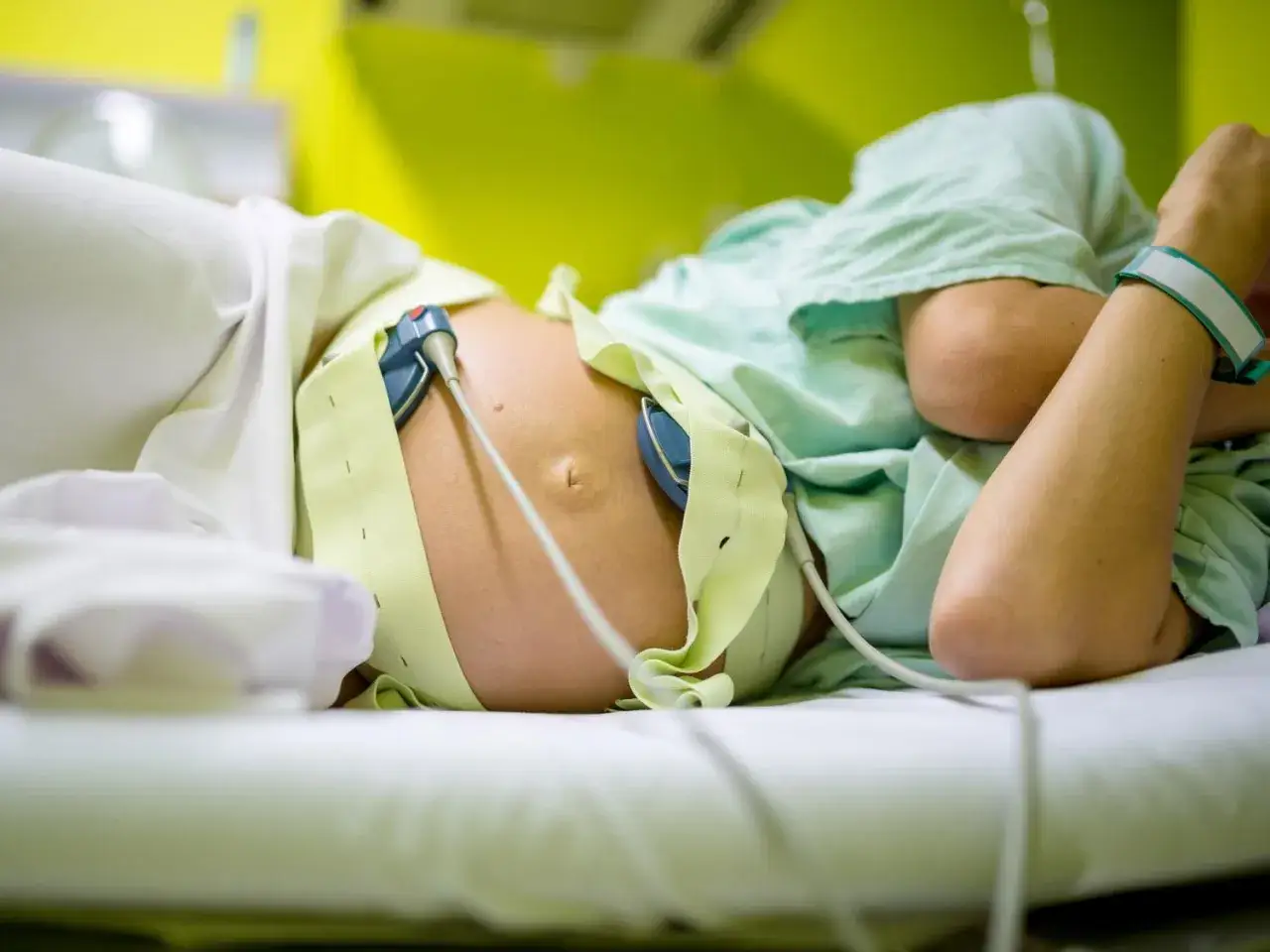 Pancia di una donna incinta con monitoraggio fetale, in attesa dell'induzione del parto.