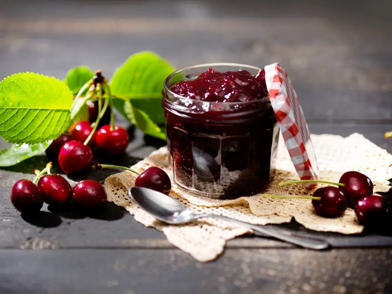 Frische Kirschen und ein Glas selbstgemachte Kirschmarmelade, bereit für ein köstliches kirschmarmelade rezept.