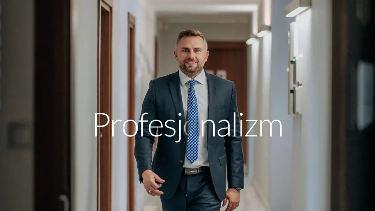Mężczyzna w garniturze idzie korytarzem, na zdjęciu napis 