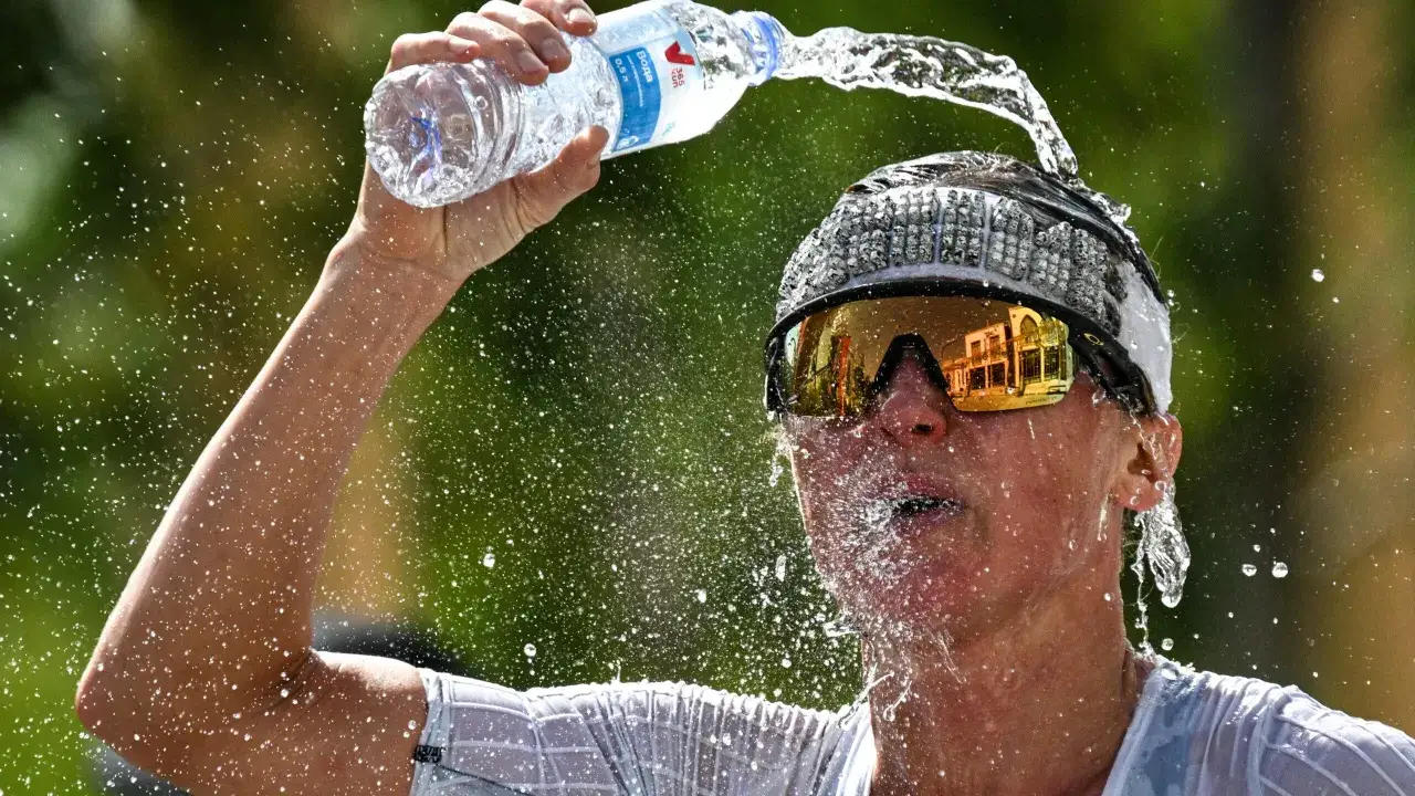 Sportlerin k&uuml;hlt sich bei gro&szlig;er Hitze mit Wasser ab, um den Puls zu senken.