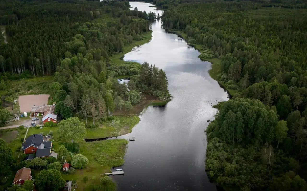 En sjö omgiven av skog, med röda hus vid strandkanten. Kanske här var finns det mest mygg i Sverige?