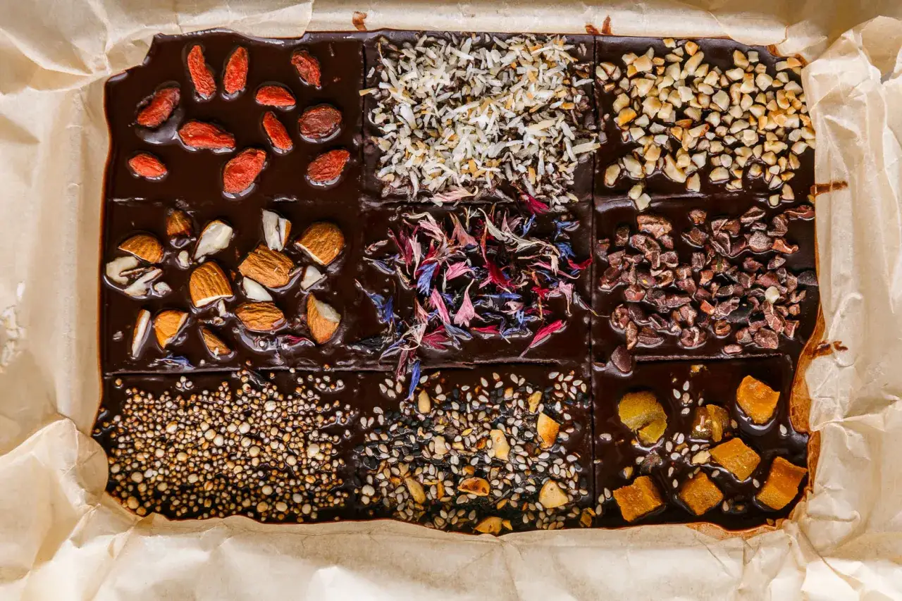 Selbstgemachte Schokolade mit Goji-Beeren, Mandeln, Kokosflocken, Blüten und Nüssen. Ein Fest für die Sinne!