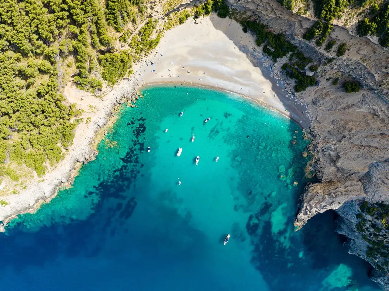 Traumhafte Mallorca Buchten mit t&uuml;rkisfarbenem Wasser, umgeben von gr&uuml;nen Pinienw&auml;ldern und felsigen K&uuml;sten. Boote ankern in der Bucht.