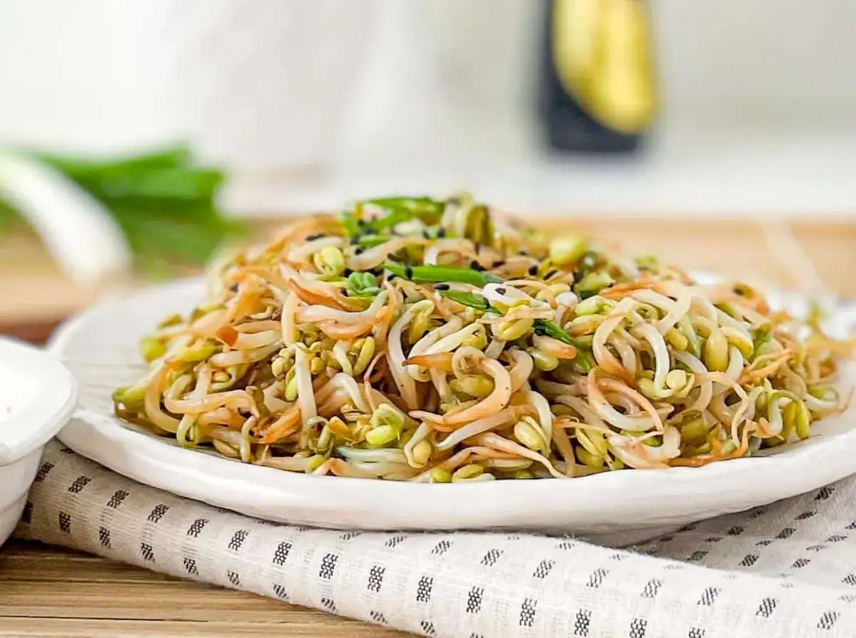 Un piatto invitante di germogli di soia saltati, guarniti con erba cipollina e semi di sesamo nero. Freschi e croccanti, un'esplosione di sapore.