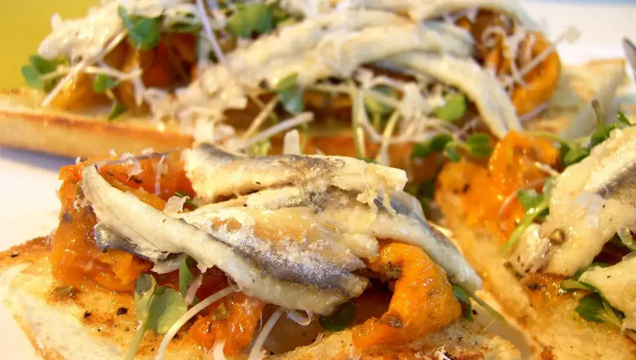 Tostadas con boquerones en salsa, tomate y brotes verdes. Un aperitivo delicioso inspirado en recetas de boquerones en salsa.