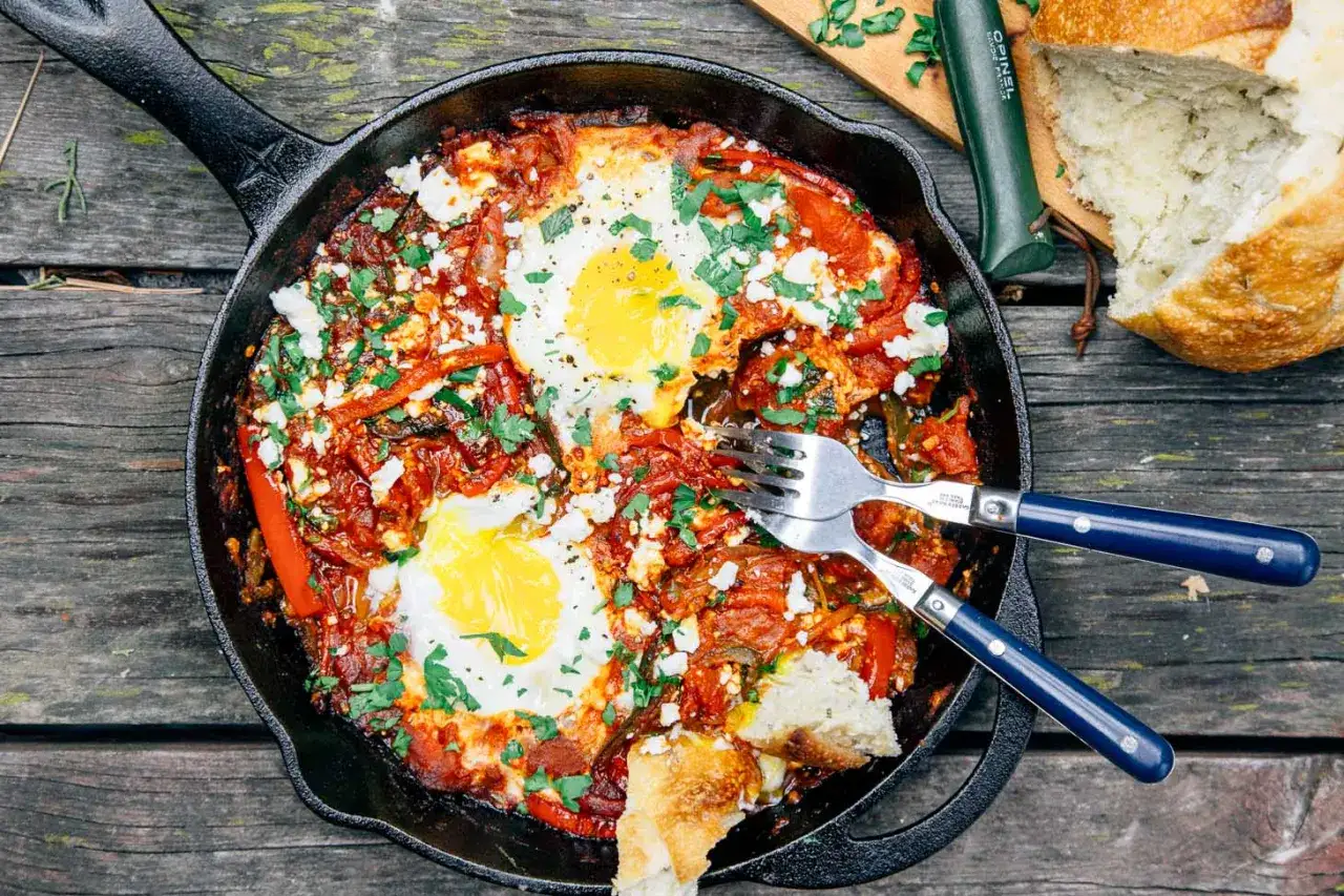 Herzhaftes Shakshuka-Rezept in Gusseisenpfanne mit pochierten Eiern, Paprika, Tomaten und Feta. Dazu frisches Brot.