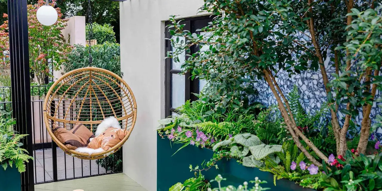 Un dondolo in vimini e piante rigogliose trasformano un piccolo balcone in un'oasi verde. Idee per come abbellire un balcone piccolo con stile e comfort.