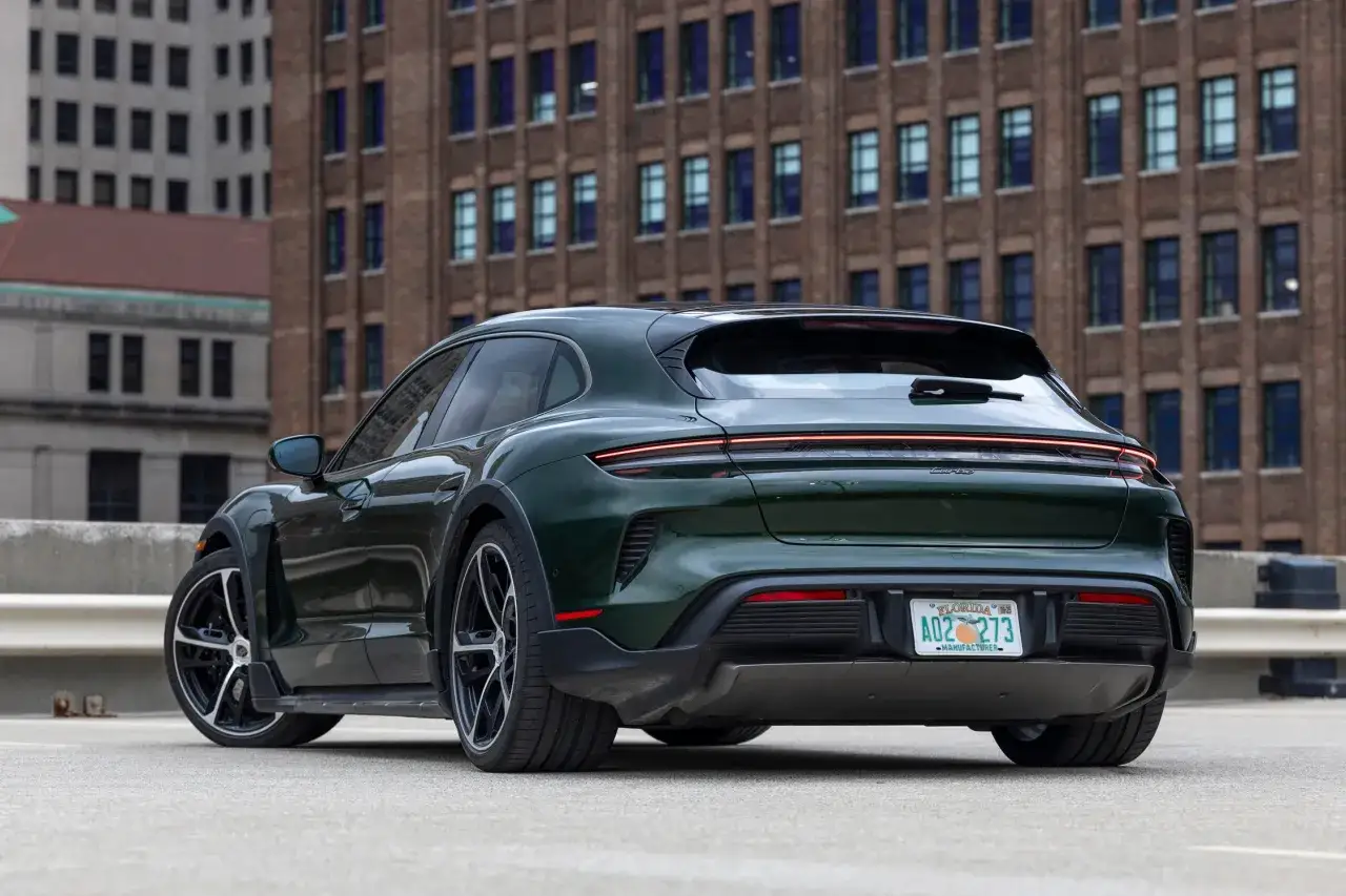 Zielony Porsche Taycan Cross Turismo z tablicą rejestracyjną z Florydy na tle ceglanego budynku.