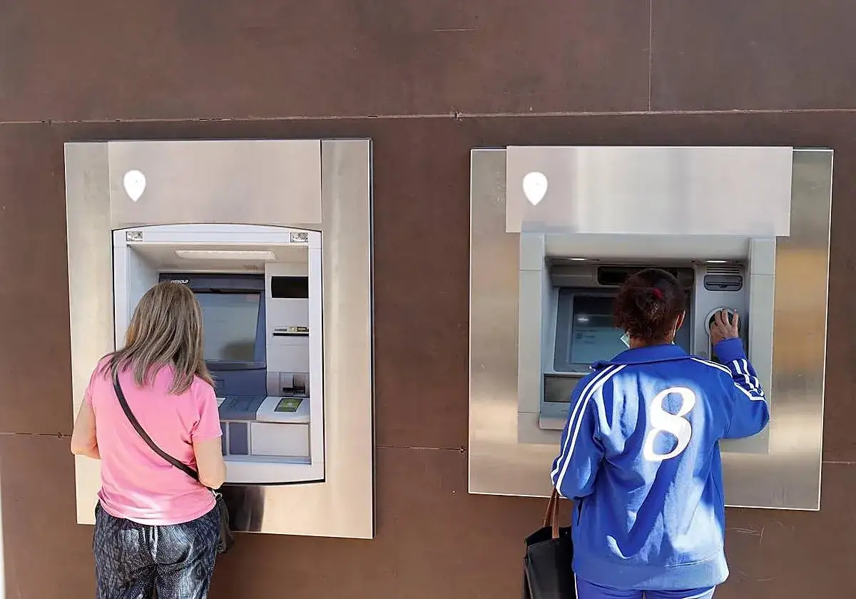 Dos mujeres usan cajeros automáticos. Una pregunta es cuánto dinero se puede sacar del cajero.