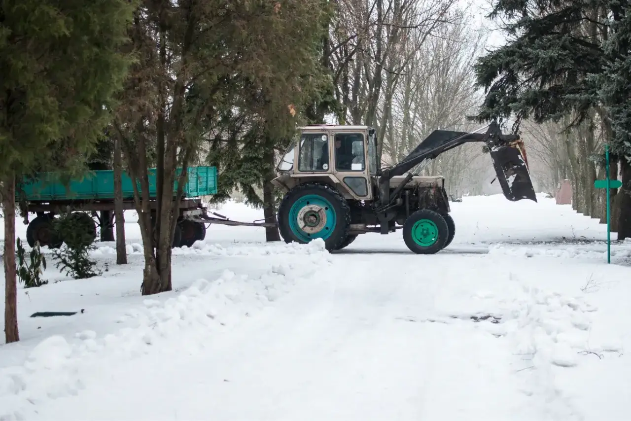 Traktor z przyczepą na śniegu. Kierowca z kategorią t prawa jazdy przygotowuje się do pracy zimą.