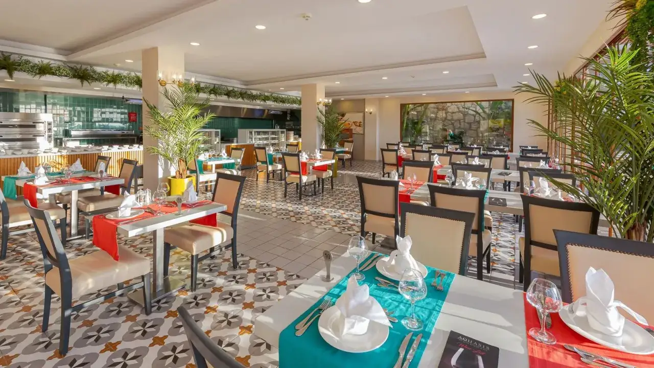 Elegancka restauracja z nakrytymi stołami, gotowa na przyjęcie gości w ramach oferty ultra all inclusive.