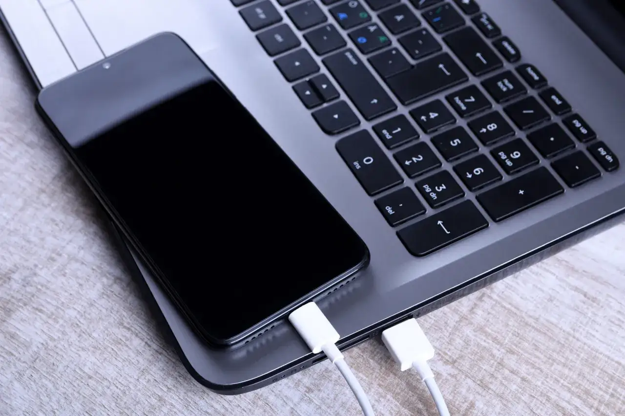 Smartfon podłączony kablem USB do laptopa. Dowiedz się, jak udostępnić internet z telefonu na komputer przez USB.