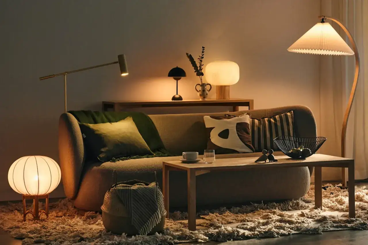 Mysig soffgrupp med flera lampor som skapar ett varmt ljus och rum. En stor golvlampa med veckat sk&auml;rm ger ett mjukt sken.