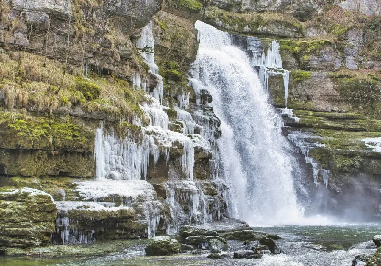 Les chutes du Doubs, un spectacle saisissant où l'eau vive rencontre la glace. Des stalactites de glace ornent les falaises rocheuses, contrastant avec la puissance de la cascade.