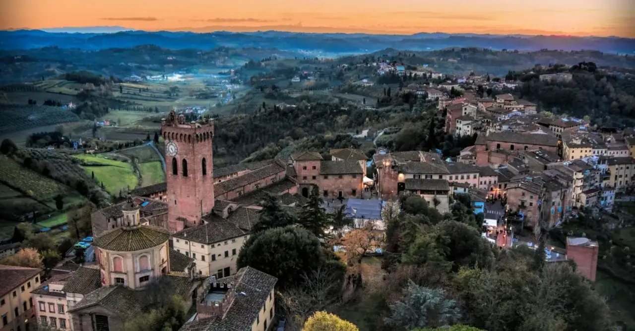 Panoramica di San Miniato al tramonto, con la torre campanaria che domina il borgo medievale e le colline toscane circostanti.
