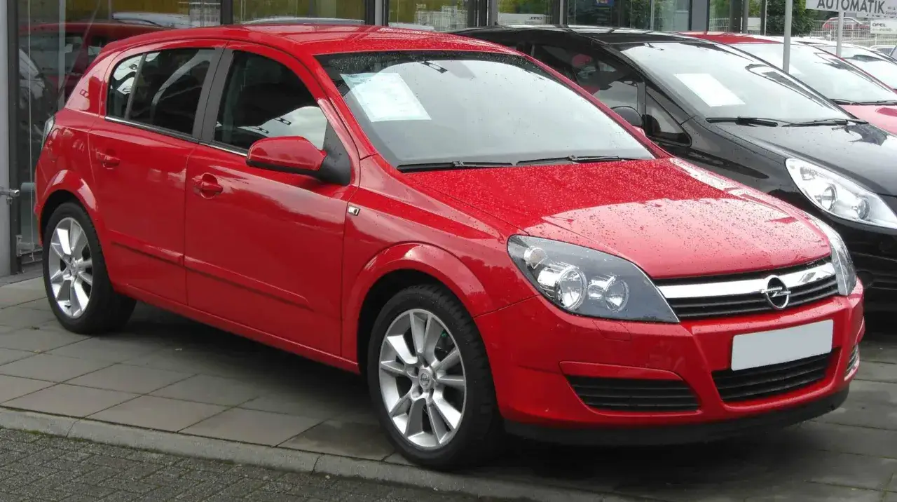 Czerwona Astra H na placu dealerskim, gotowa do akcji serwisowej.