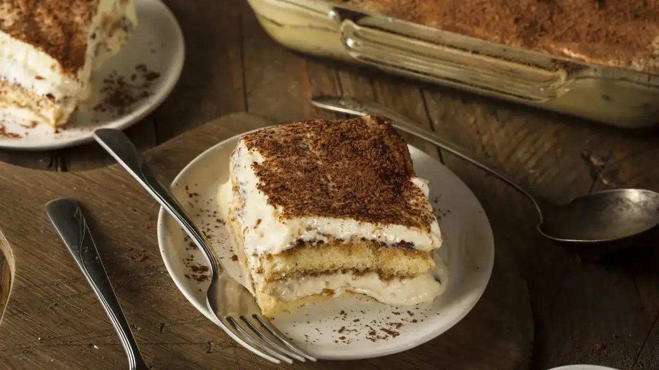 Une part de tiramisu, dessert iconique dont l'origine est d&eacute;battue, sur une assiette avec une fourchette.