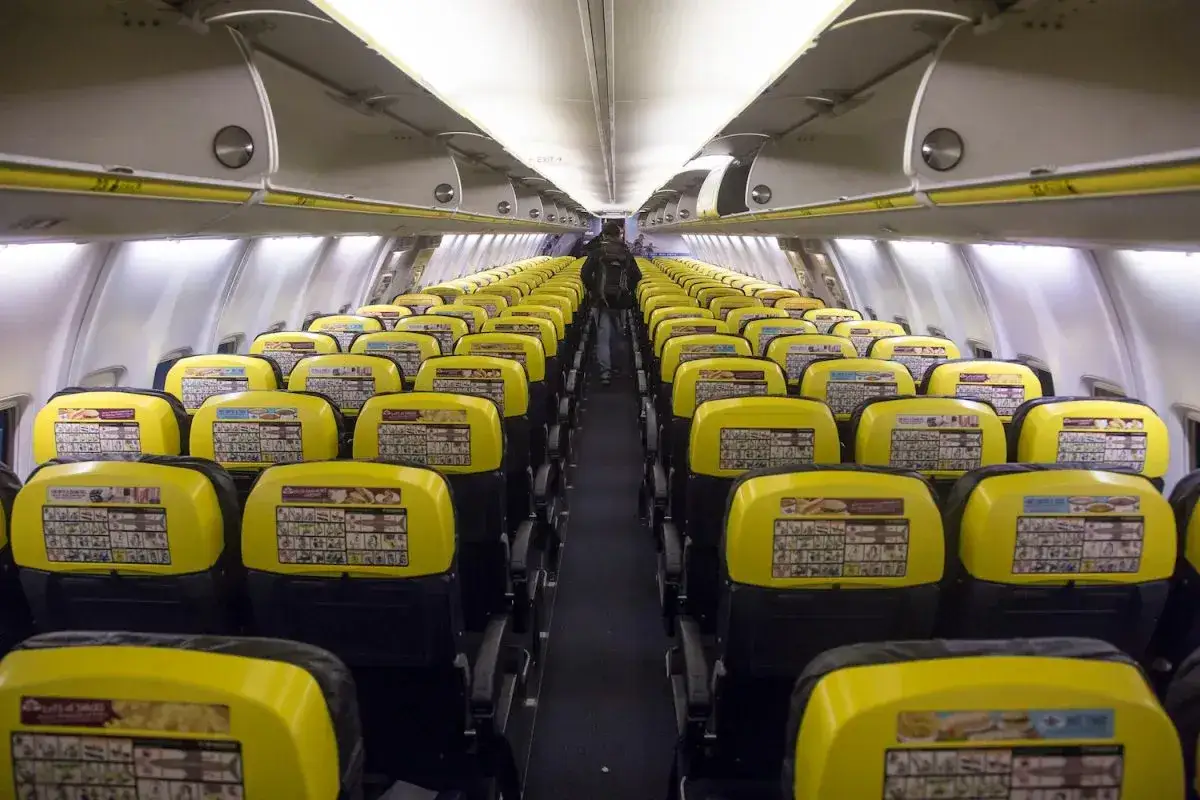 Rzędy żółtych **Ryanair seats** w pustym samolocie. Widać instrukcje bezpieczeństwa na oparciach.