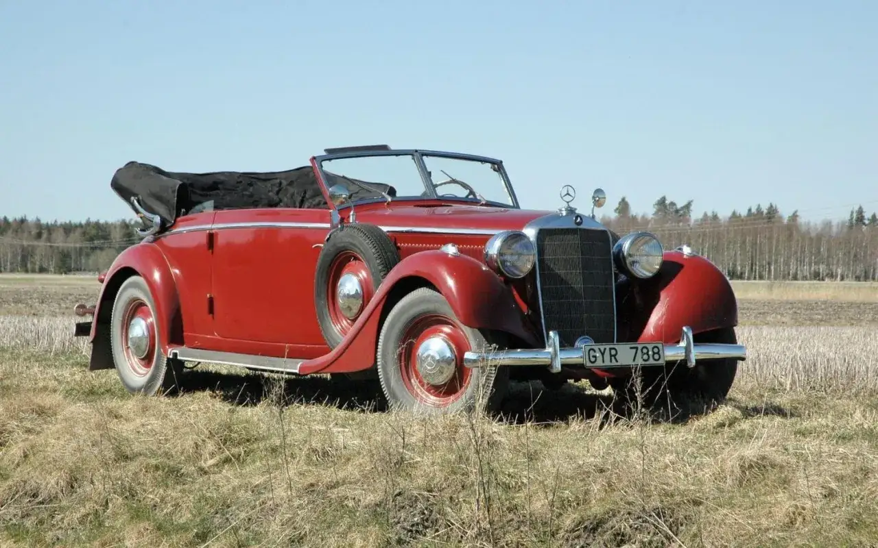 Röd cabriolet, en av de äldre tyska bilarna, står på ett fält.