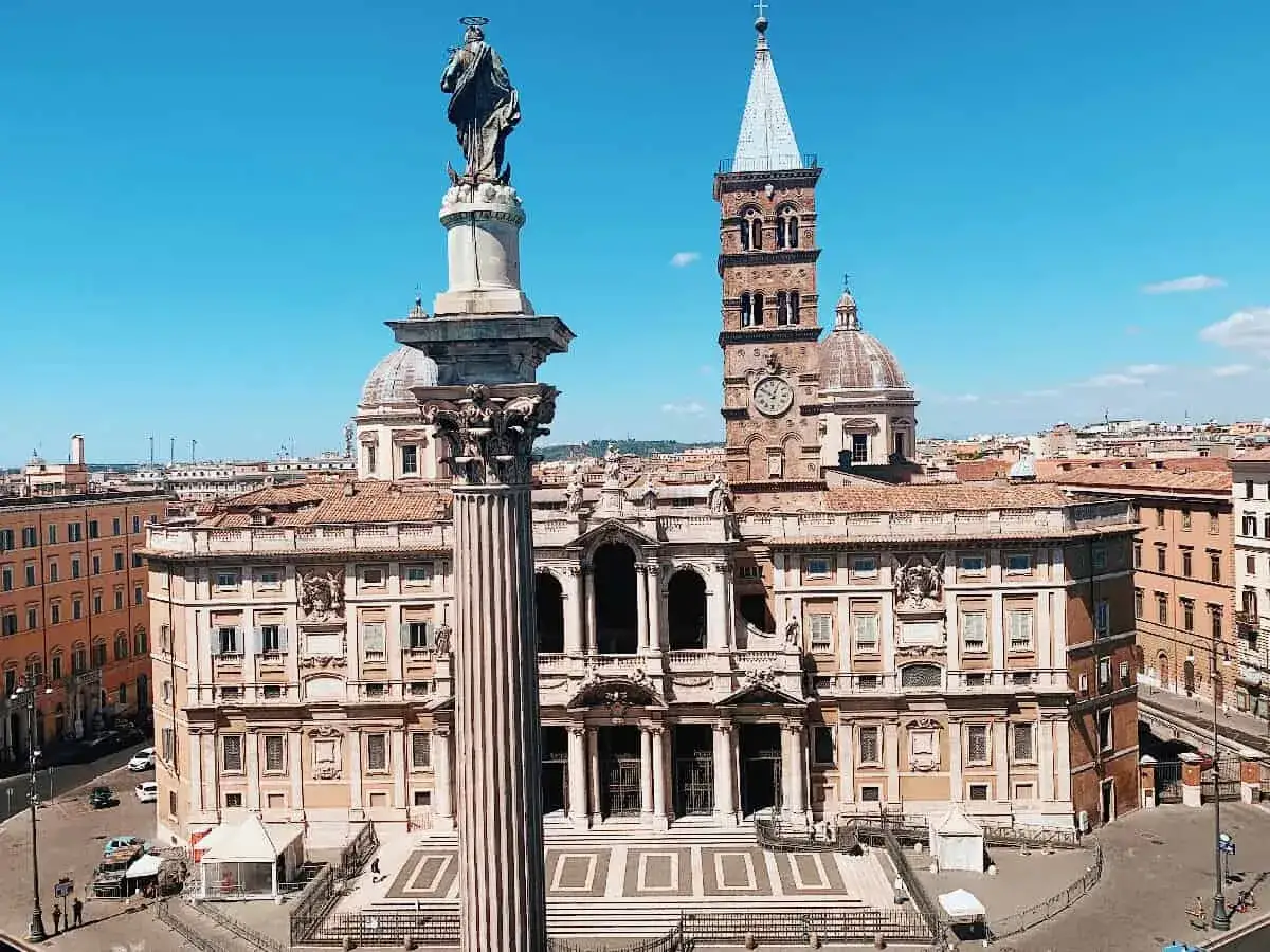 La maestosa basilica di Santa Maria Maggiore a Roma, con la sua imponente colonna e la torre campanaria, domina il cielo azzurro.