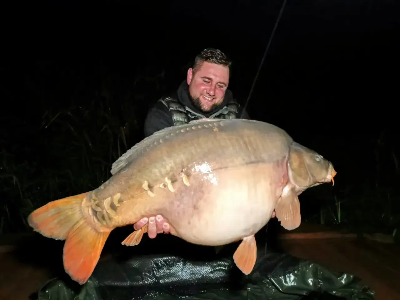 Szczęśliwy wędkarz z ogromnym karpiem złowionym na łowisku Extra Carp Radymno.