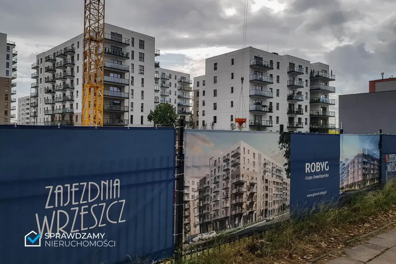 Budowa osiedla mieszkaniowego w Gdańsku z żurawiem i banerami deweloperów.