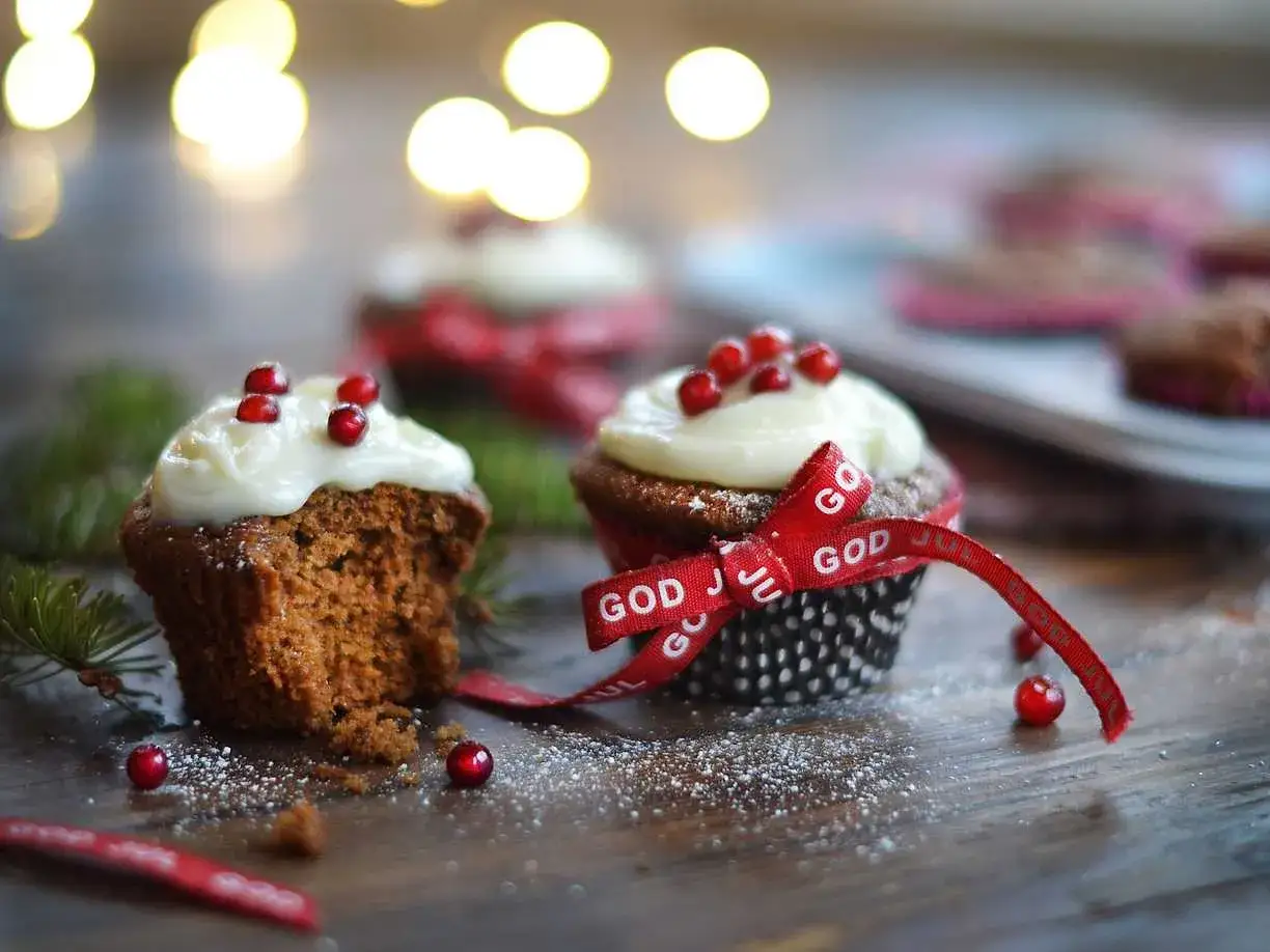 Julmuffins med vit frosting och röda bär, dekorerade med ett rött band med texten 