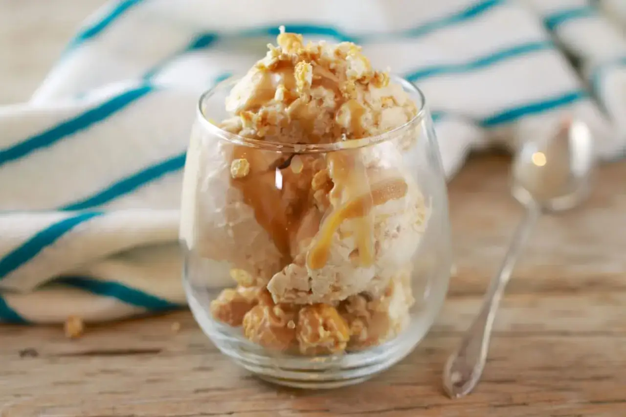 Cremiges Popcorn Eis mit Karamellsauce und knusprigen Popcorn-Stückchen in einem Glas.