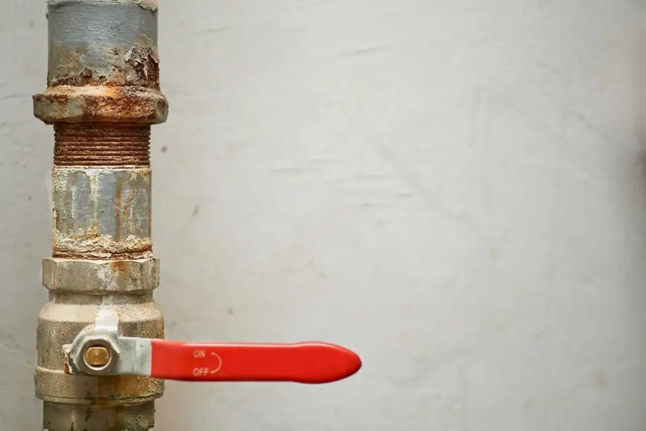 Tuber&iacute;a de metal oxidada con una llave de paso roja. La llave de paso del agua es comunitaria y est&aacute; marcada con 