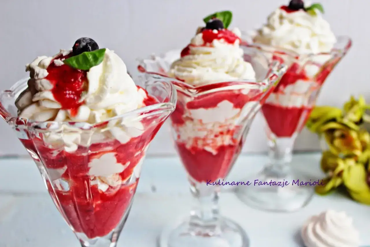 Pyszny Eton Mess w pucharkach: warstwy bitej śmietany, pokruszonej bezy i truskawkowego sosu, udekorowane owocami.