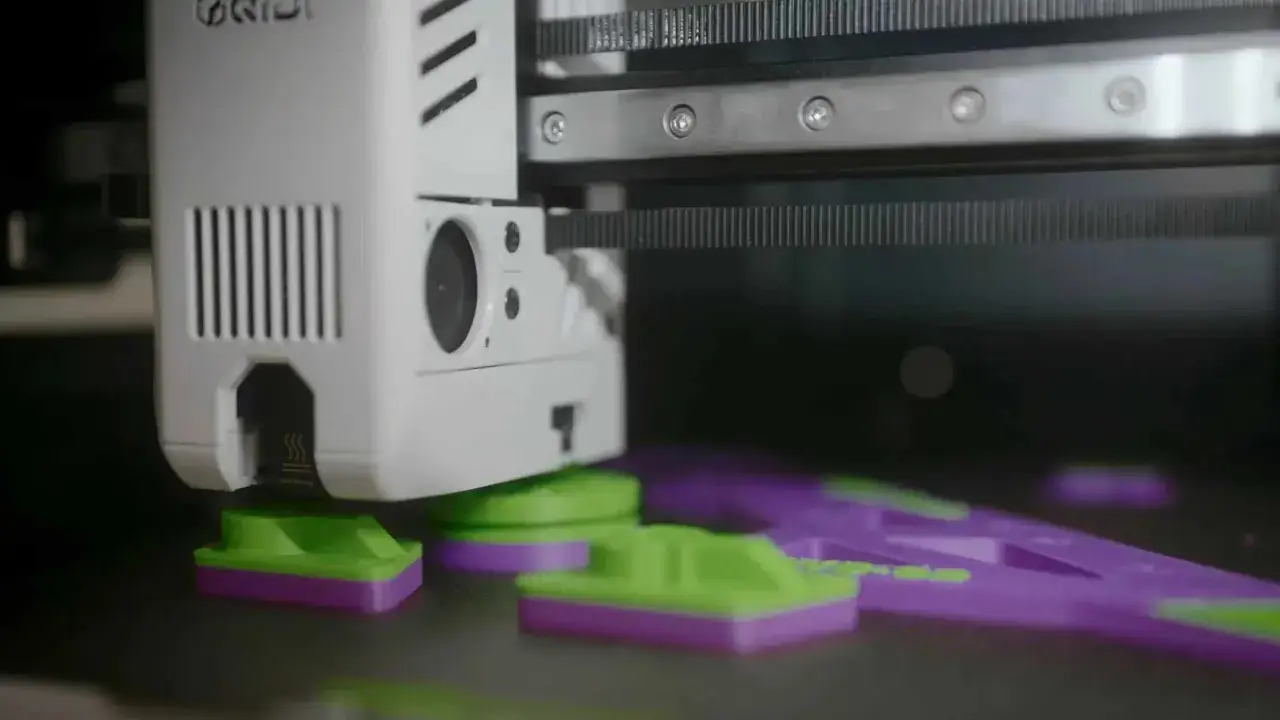 Drukarka 3D tworzy wytrzymałe elementy z tworzywa ABS. Zielono-fioletowe wydruki są gotowe do użycia.