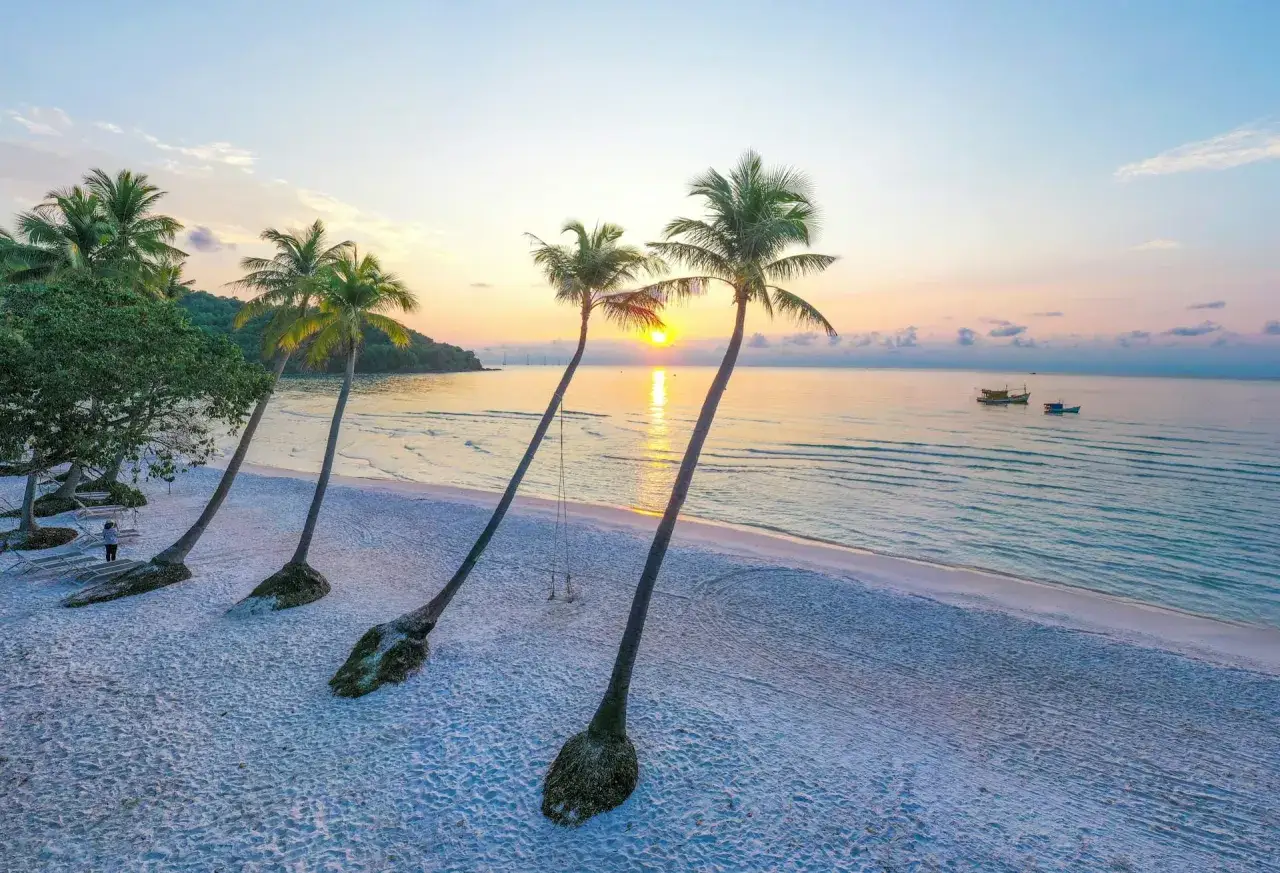 Zachód słońca na plaży Phu Quoc, idealny czas na relaks. Palmy, piasek i spokojne morze.