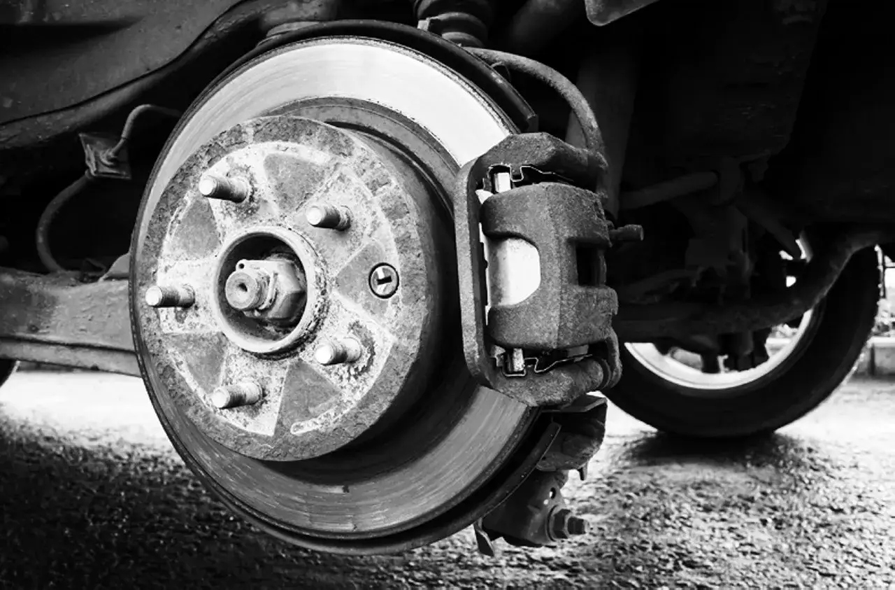 Primer plano de un disco de freno y pinza de coche. El ferodo, esencial para frenar, se ve desgastado.