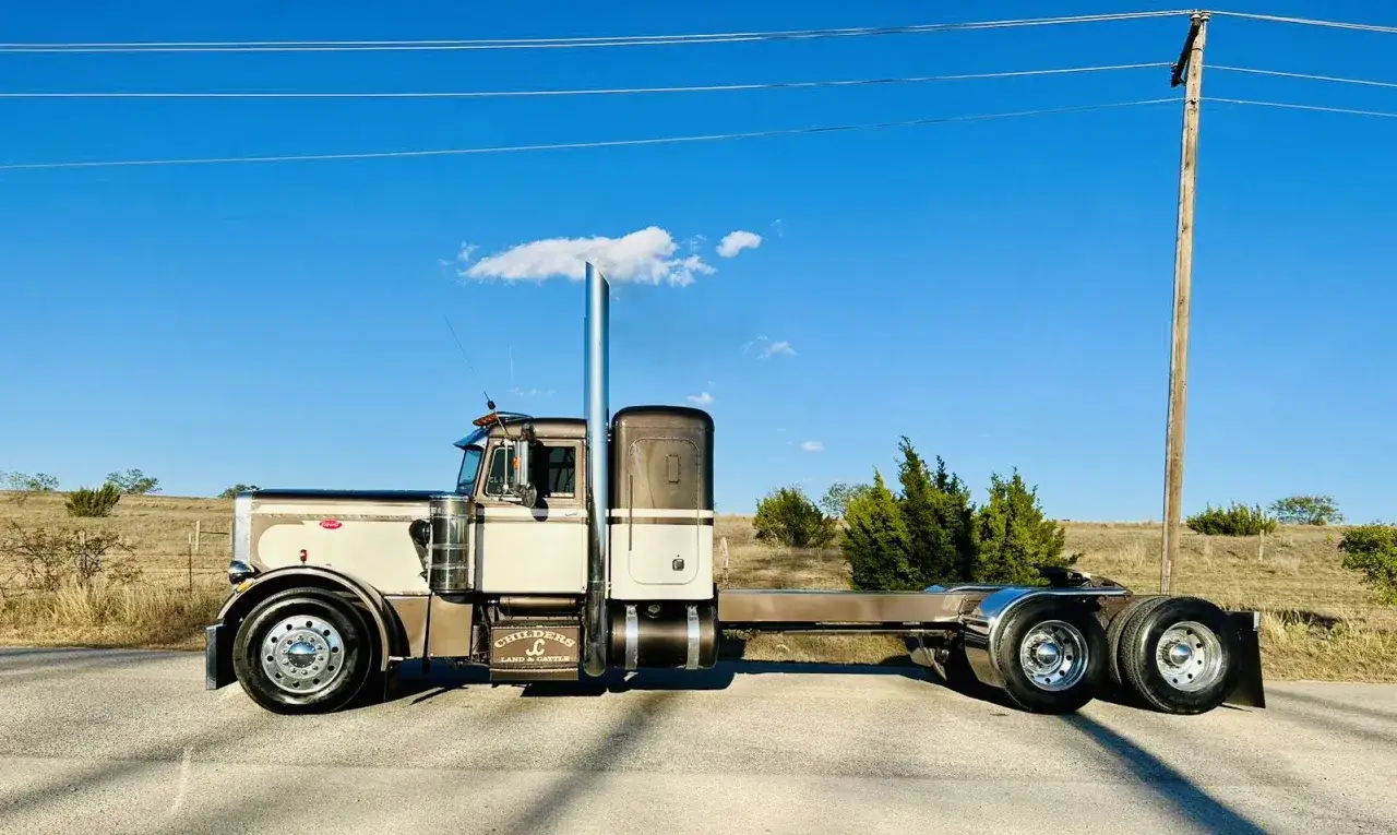 Un camion am&eacute;ricain tuning, un Peterbilt chrom&eacute; et bicolore, pr&ecirc;t pour la route sous un ciel bleu.