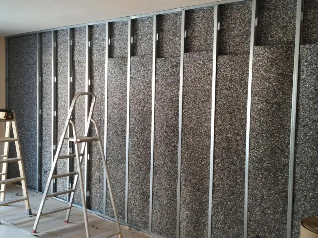 Instalación de aislamiento acústico en una pared, con estructura metálica y paneles de corcho granulado, ideal para como aislar una pared del ruido de los vecinos.