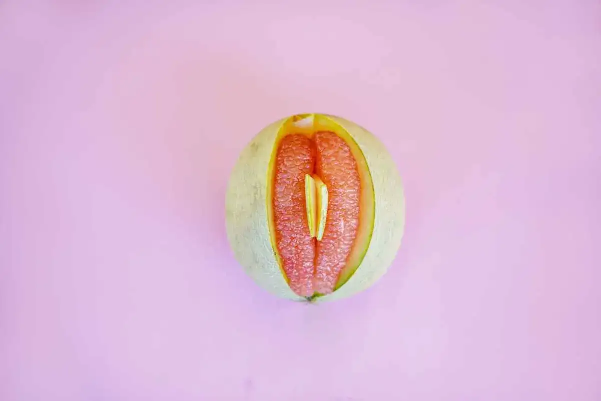 En melon skuren på mitten, med saftigt rött fruktkött som påminner om ett svullet underliv, kanske en symbol för graviditet.