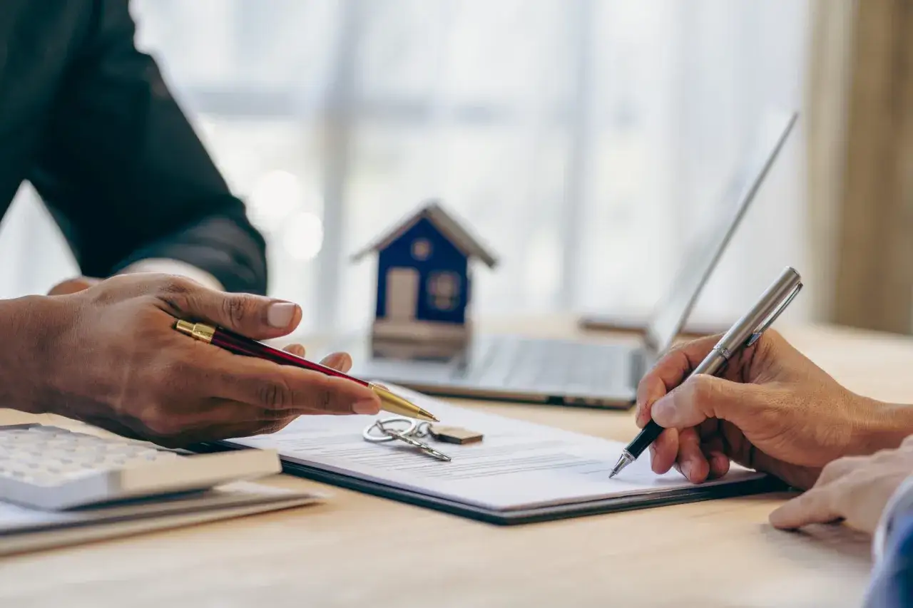 Signature d'un prêt immobilier. Quel salaire pour emprunter 200 000 euros ? Clés, maison modèle et calculatrice sur le bureau.